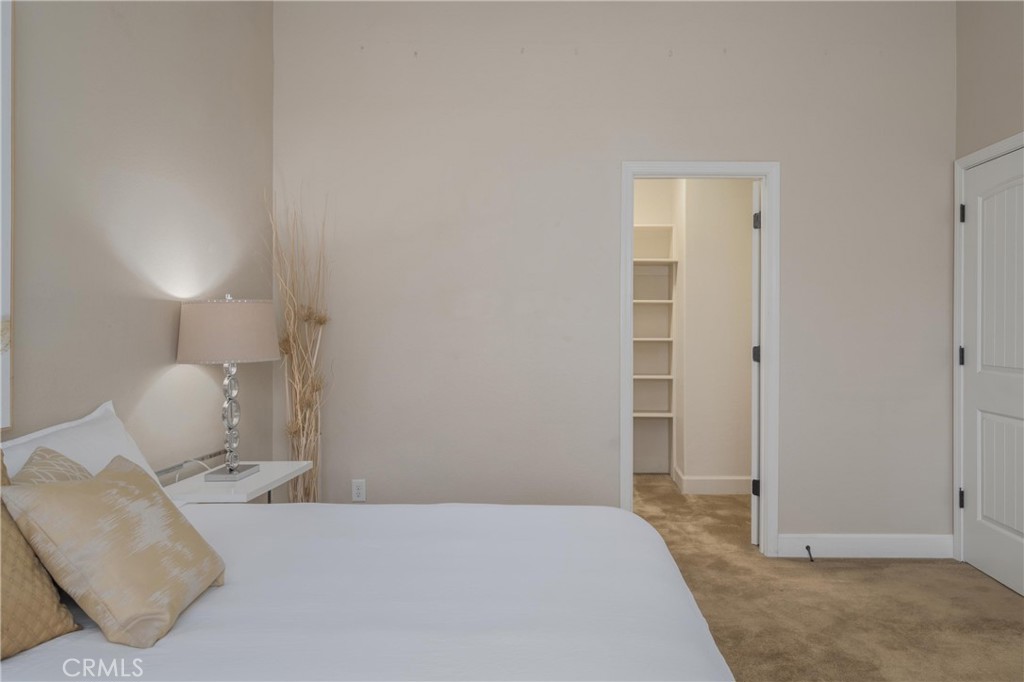 Staged bedroom with a white bed, gold accent pillows, and an open closet doorway.