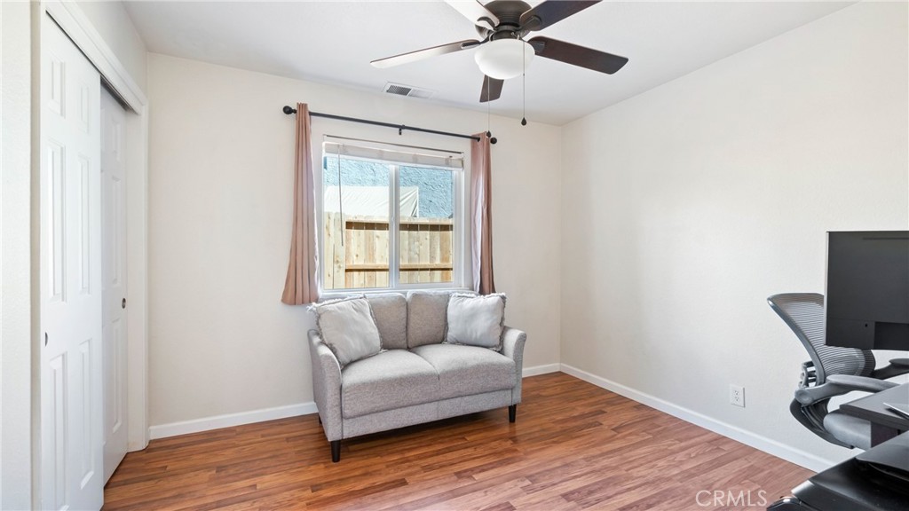 Furnished room with a gray loveseat under a window and a computer workstation.