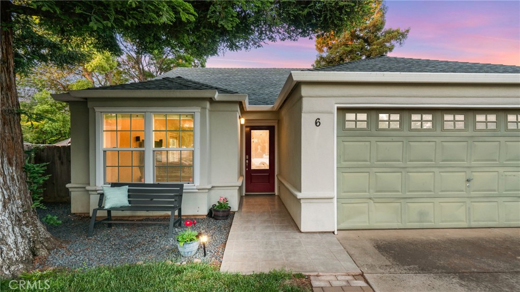 Home exterior with a red entry door, attached garage, and bench beneath the front window.