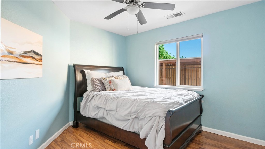 Bedroom with pale blue walls, a dark wood bed, white bedding, and a window overlooking a wooden fence.