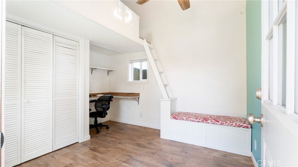 Bedroom with a built-in daybed, loft ladder, desk, and louvered closet doors.