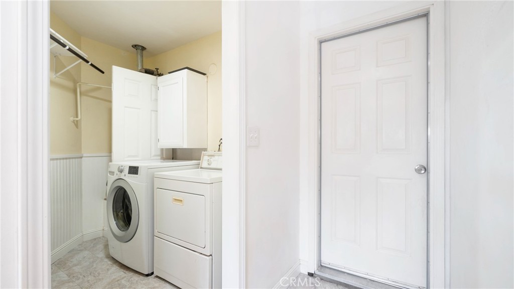 Laundry room with a front-loading washer and dryer beside a white six-panel door.