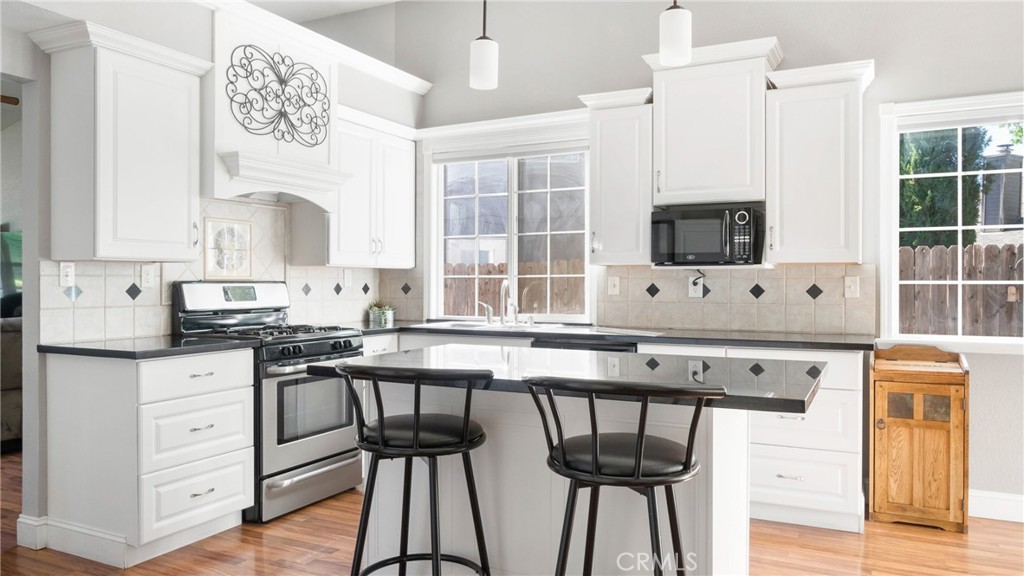 Kitchen with white cabinets, black countertops, a breakfast bar, and two black stools.