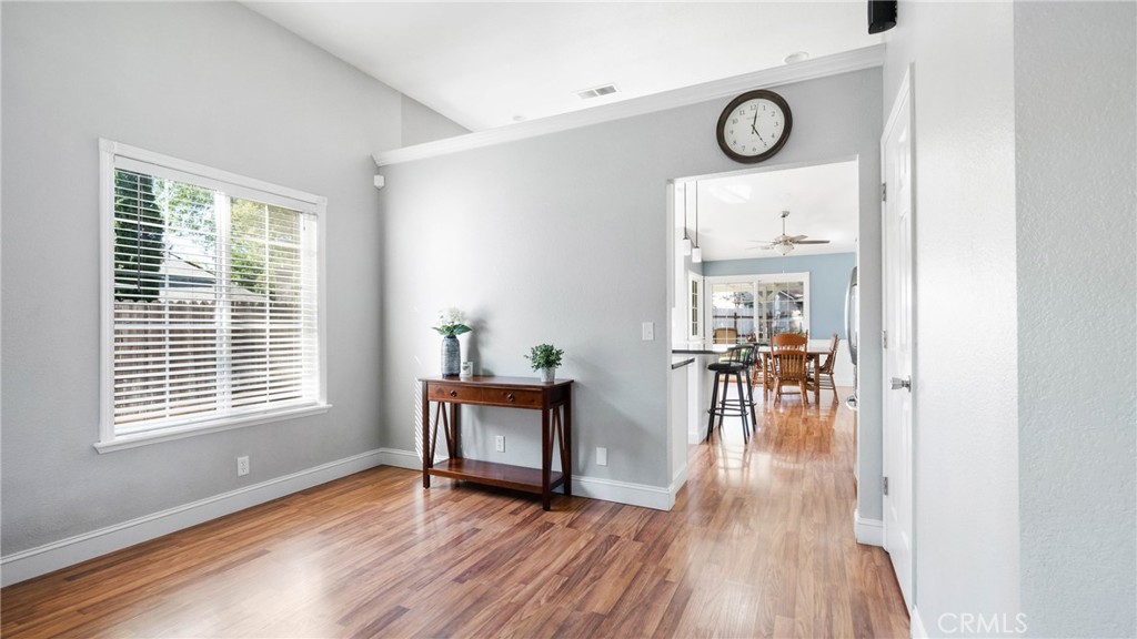 Entryway with wood flooring, a console table, and a view into the dining area.