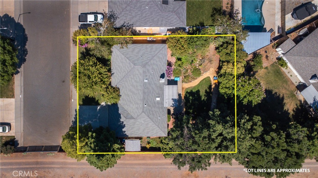 Aerial view of a home and landscaped lot outlined in yellow, with the roof and backyard visible.