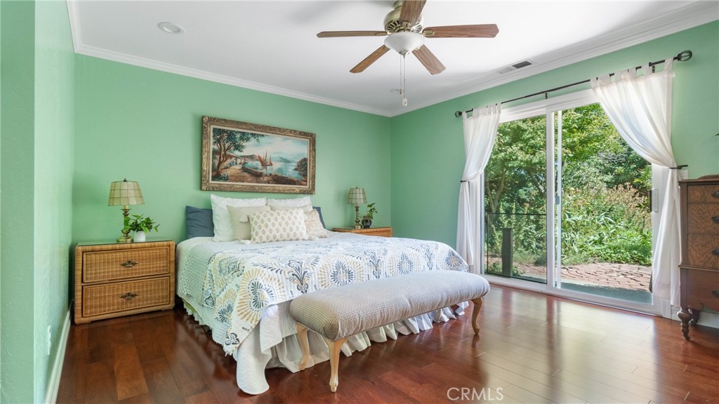 Bedroom with mint-green walls, a patterned bedspread, and sliding glass doors overlooking a leafy garden.