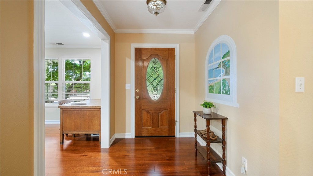 Entry foyer with hardwood floors, a decorative-glass wooden front door, and an arched window.