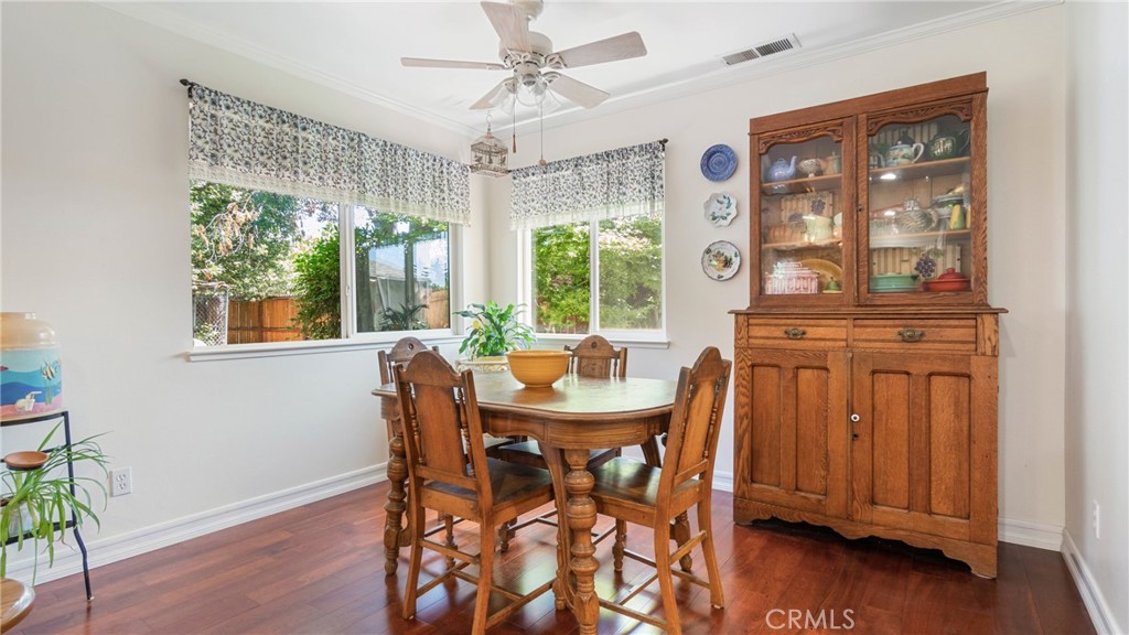 Dining room with a wooden table, glass-front china cabinet, patterned valances, and hardwood floors.