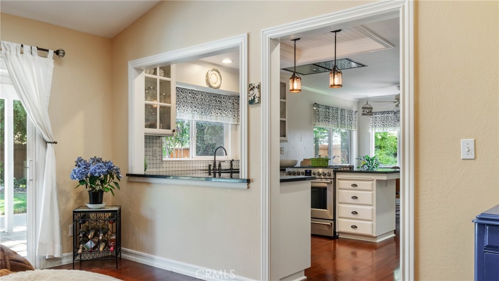 Kitchen with white cabinets, stainless steel appliances, pendant lights, and hardwood floors.