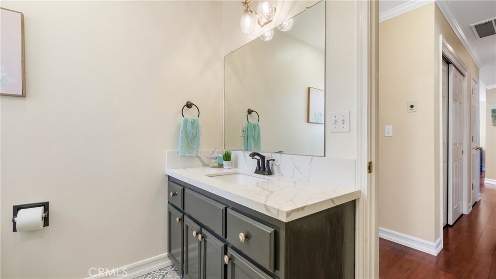 Bathroom vanity with dark cabinets, a marble-look counter, black faucet, and teal hand towel.