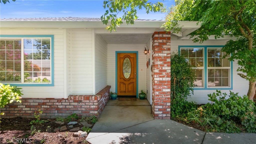 Home entrance with a carved wooden door, brick accents, and teal-trimmed windows.