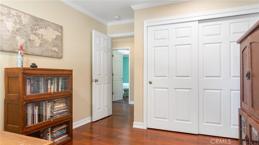 Room with white paneled closet doors, wood floors, and bookcases beneath a large world map.