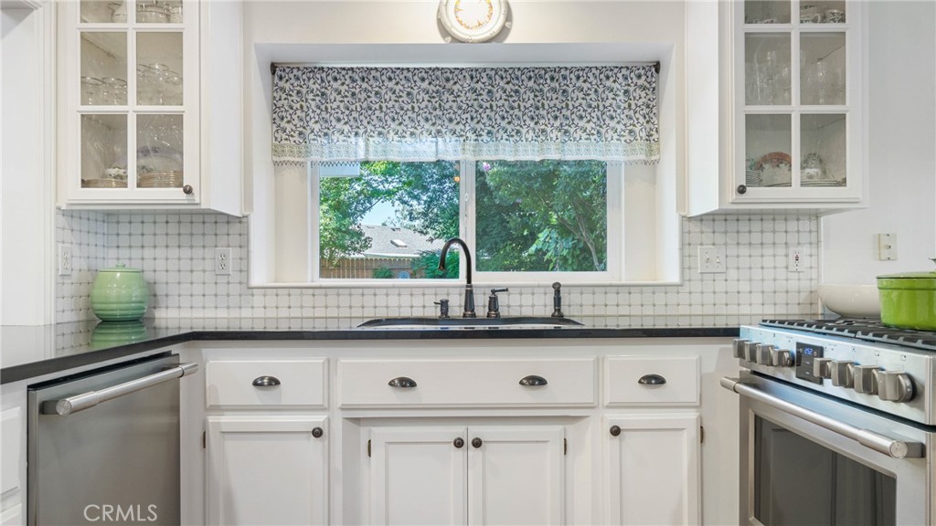 Bright kitchen with white cabinets, stainless-steel appliances, and a window above the sink.