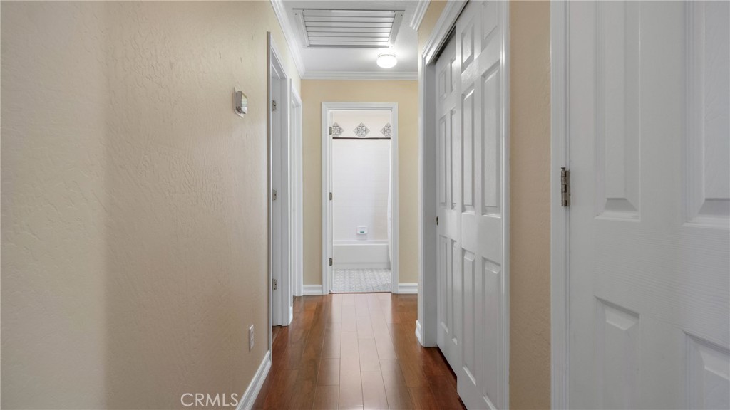 Hallway with warm wood flooring and white paneled doors, looking toward a bathroom.