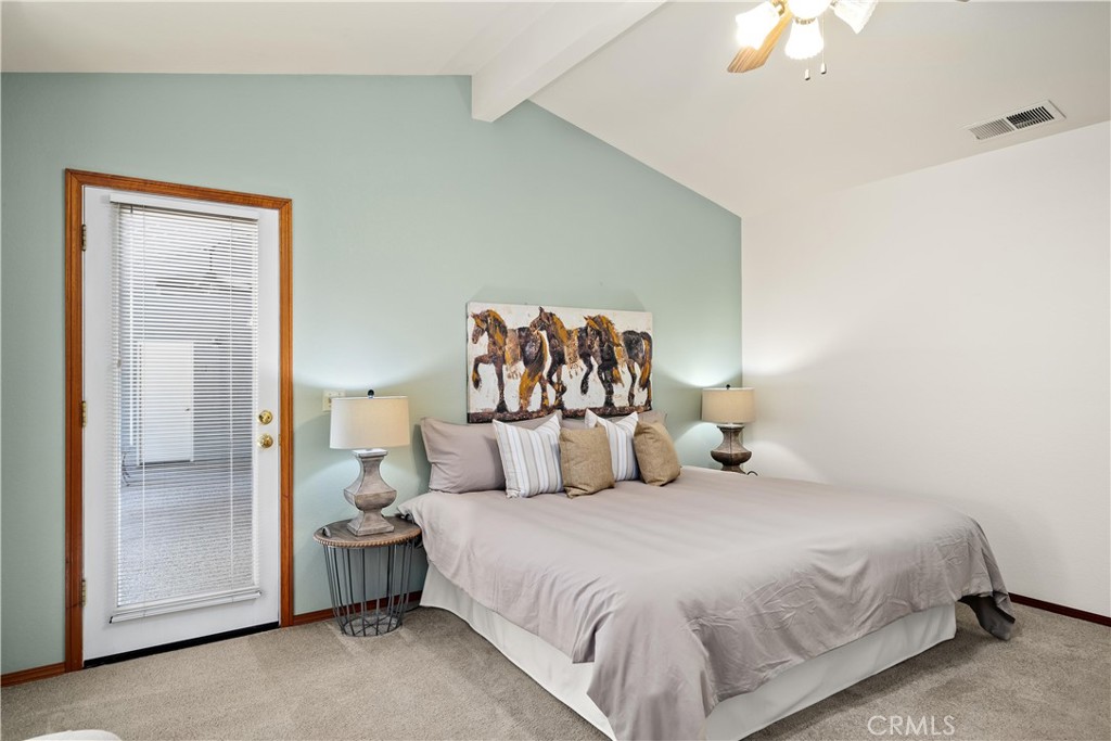 Staged bedroom with a king-size bed, horse artwork, and a glass-paneled door with blinds.