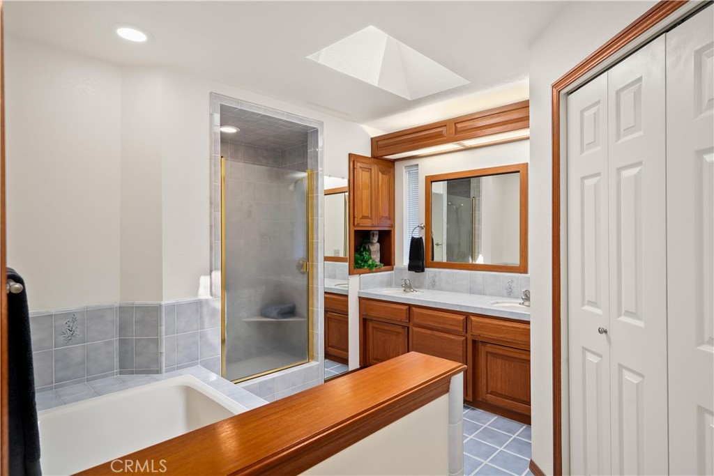 Bathroom with a tiled shower, soaking tub, and wood vanity.