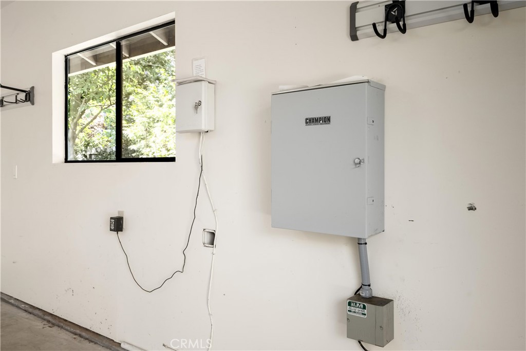 Garage wall with a large electrical panel, utility boxes, and a window overlooking trees.