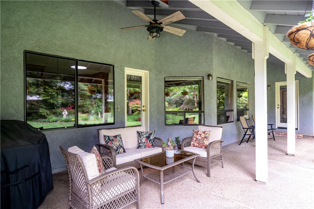 Covered patio with wicker seating, a ceiling fan, and views of the garden.