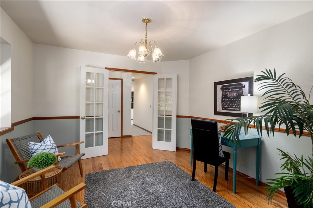 Home office with French doors, a teal desk, and warm wood flooring.