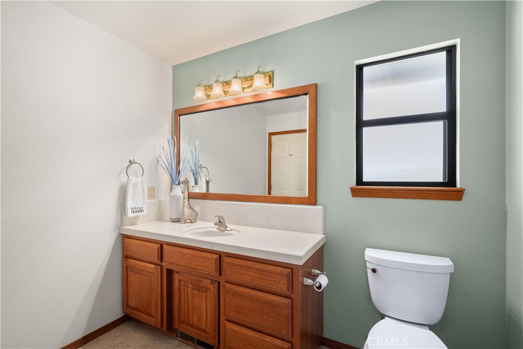 Bathroom with a wood vanity, white sink, wood-framed mirror, and sage-green wall.