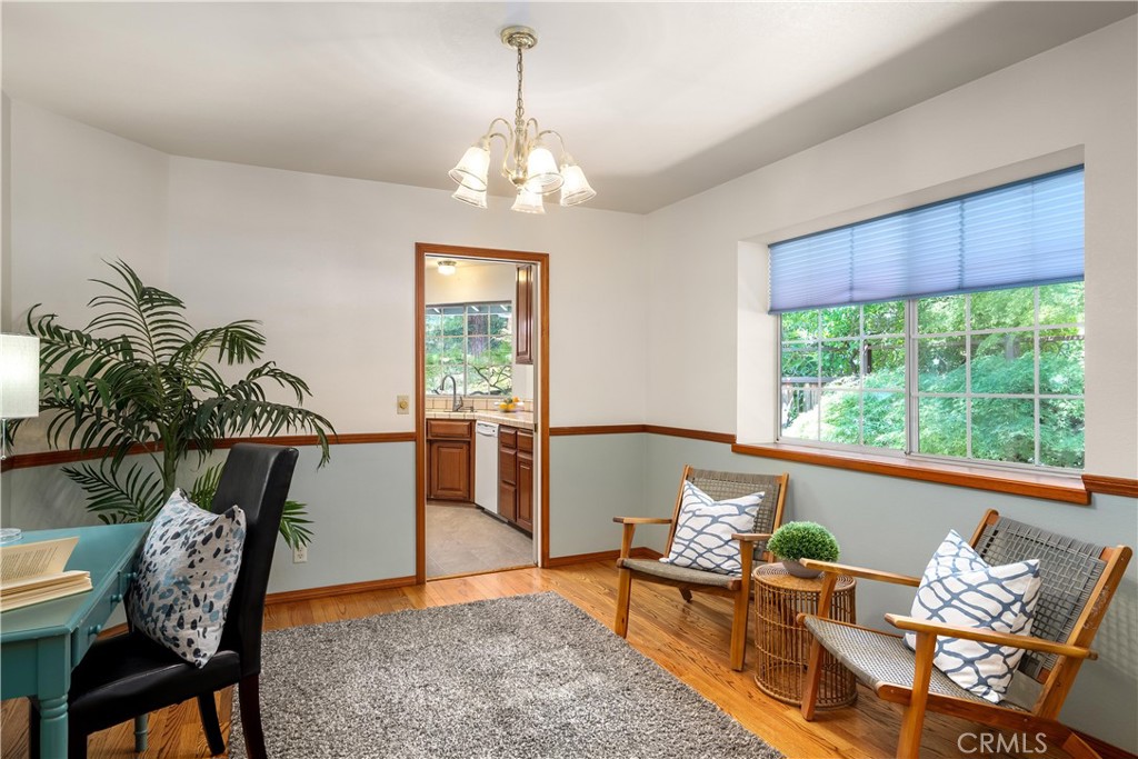 Sitting room with wood-framed chairs, hardwood floors, and a large window overlooking greenery.