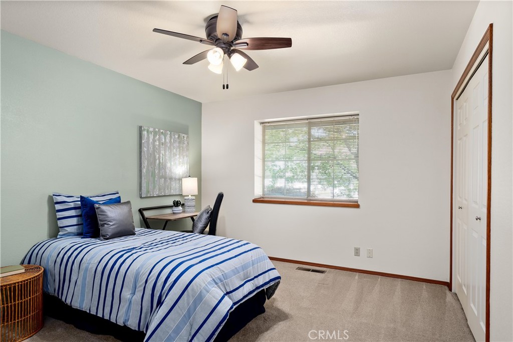 Bedroom with blue-and-white striped bedding, a ceiling fan, and a window with blinds.