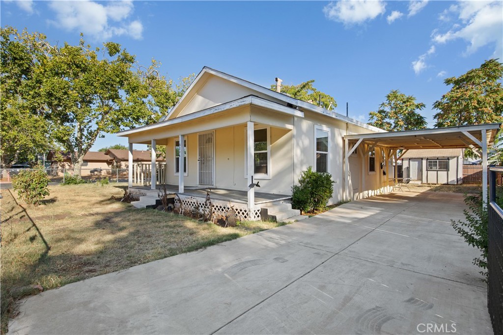 Single-story white house with a covered porch and long driveway leading to a carport.