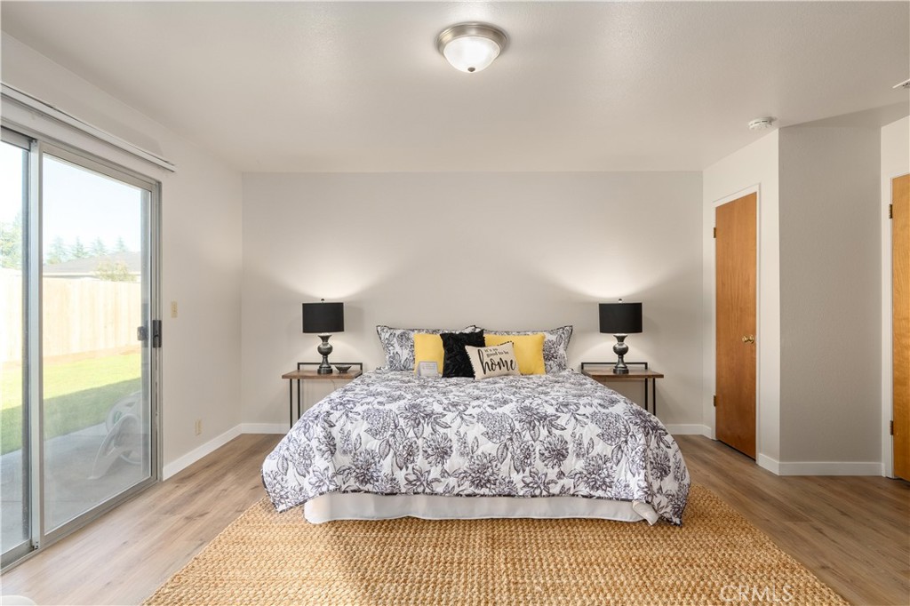 Staged bedroom with floral bedding, matching bedside lamps, and a sliding glass door to the yard.