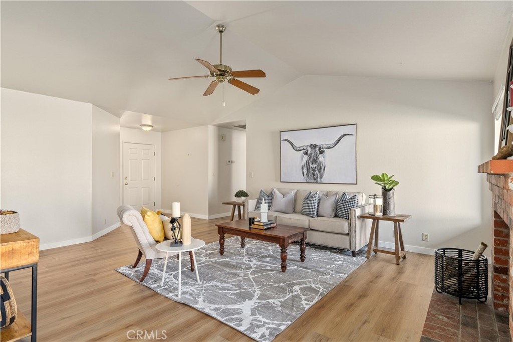 Living room with gray seating, a patterned rug, ceiling fan, and brick fireplace.