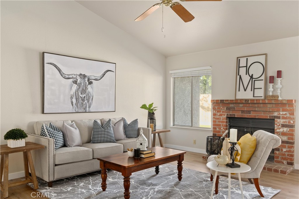 Staged living room with a brick fireplace, gray sofa, and framed longhorn print.