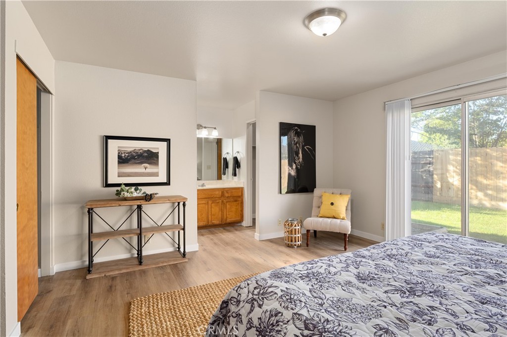 Bedroom with a patterned bed, yellow-accented chair, and sliding glass door to the backyard.