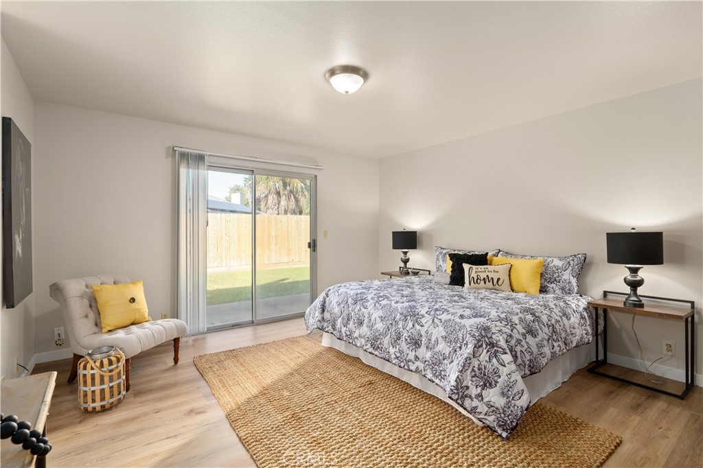 Staged bedroom with a floral bed, tufted chair, and sliding glass doors to the backyard.