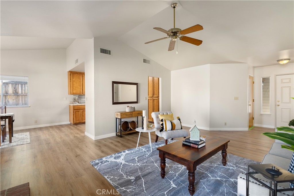 Furnished living room with vaulted ceiling, ceiling fan, and open kitchen area