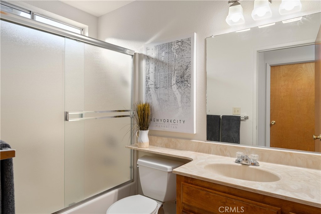 Bathroom with glass shower doors, a wooden vanity, and a framed New York City map.