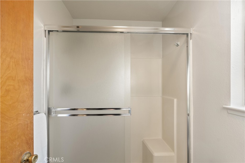 Bathroom shower with a sliding frosted-glass door, chrome trim, and built-in seat.