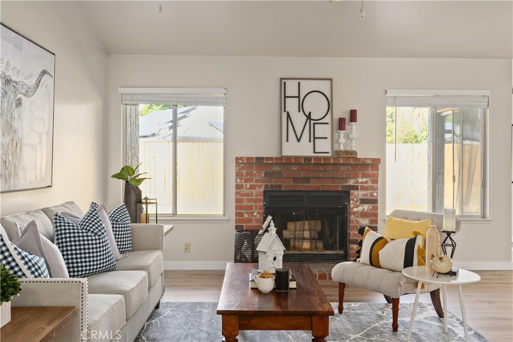 Furnished living room with a red brick fireplace, two sofas, and large windows.