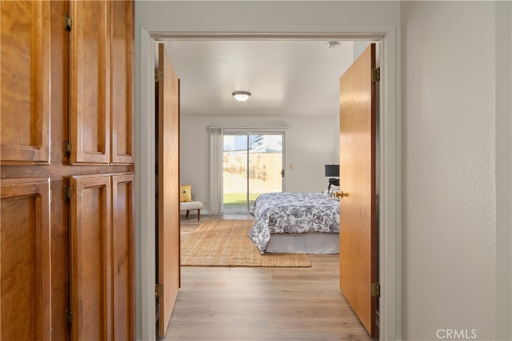 Bedroom with a floral bedspread, woven rug, and sliding glass door to a fenced yard.
