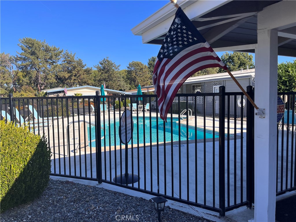 Outdoor pool behind a black metal fence, with an American flag hanging from the patio.