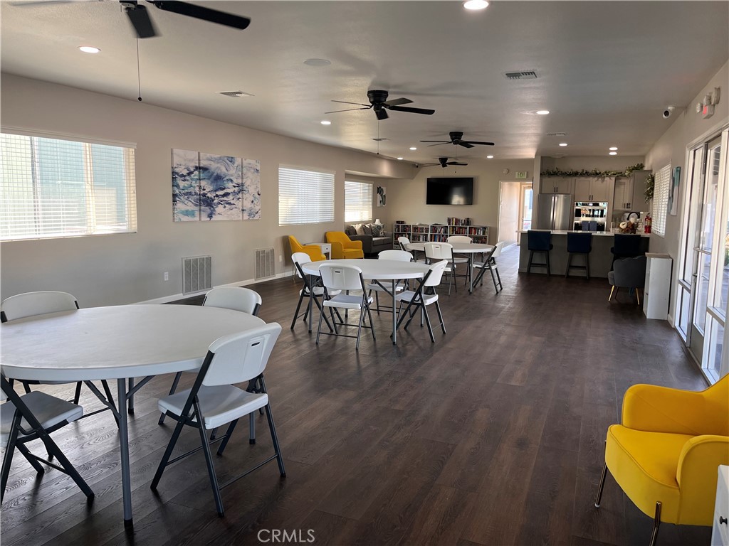 Community lounge with dining tables, yellow armchairs, and a kitchenette.