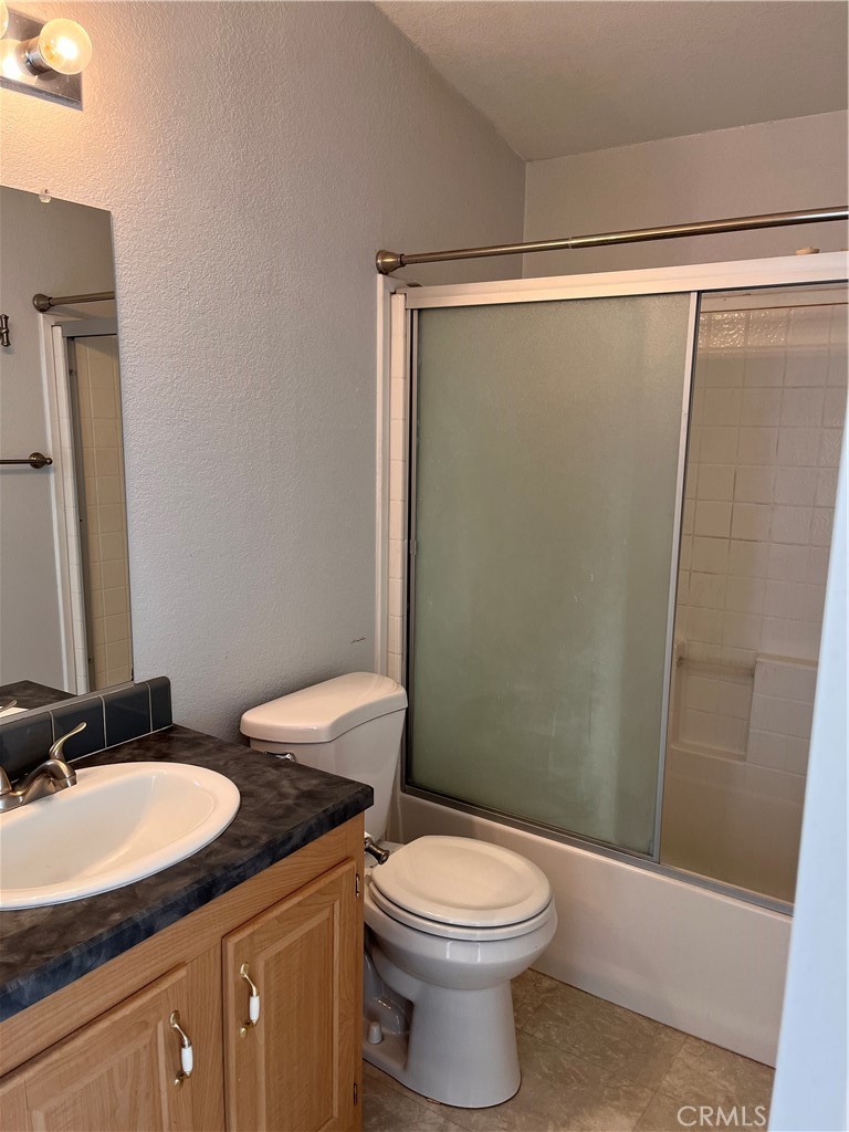 Bathroom with a wood vanity, white sink and toilet, and frosted-glass sliding shower doors.
