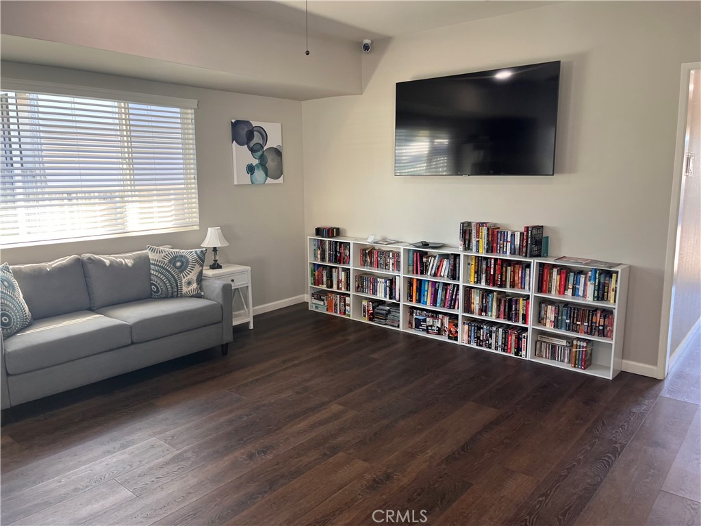 Furnished living room with a gray sofa, wall-mounted television, and low bookshelves filled with books.
