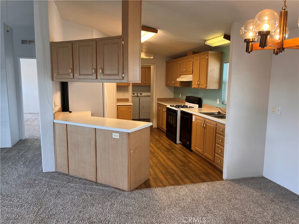 Kitchen with light wood cabinets, a white peninsula, and wood-look flooring.