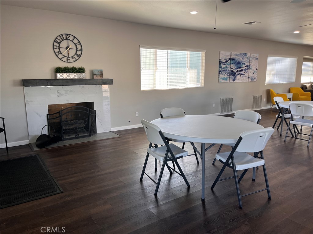 Dining area with a white table and folding chairs beside a marble-look fireplace.