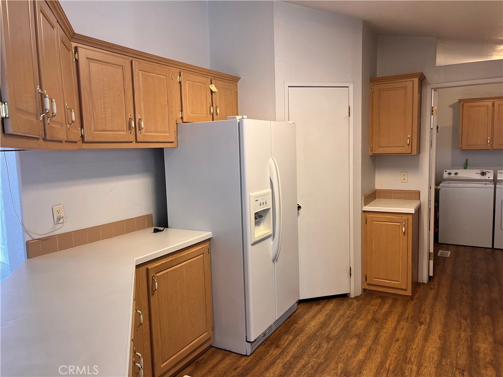 Kitchen with wood cabinets, white refrigerator, and an adjacent laundry area.