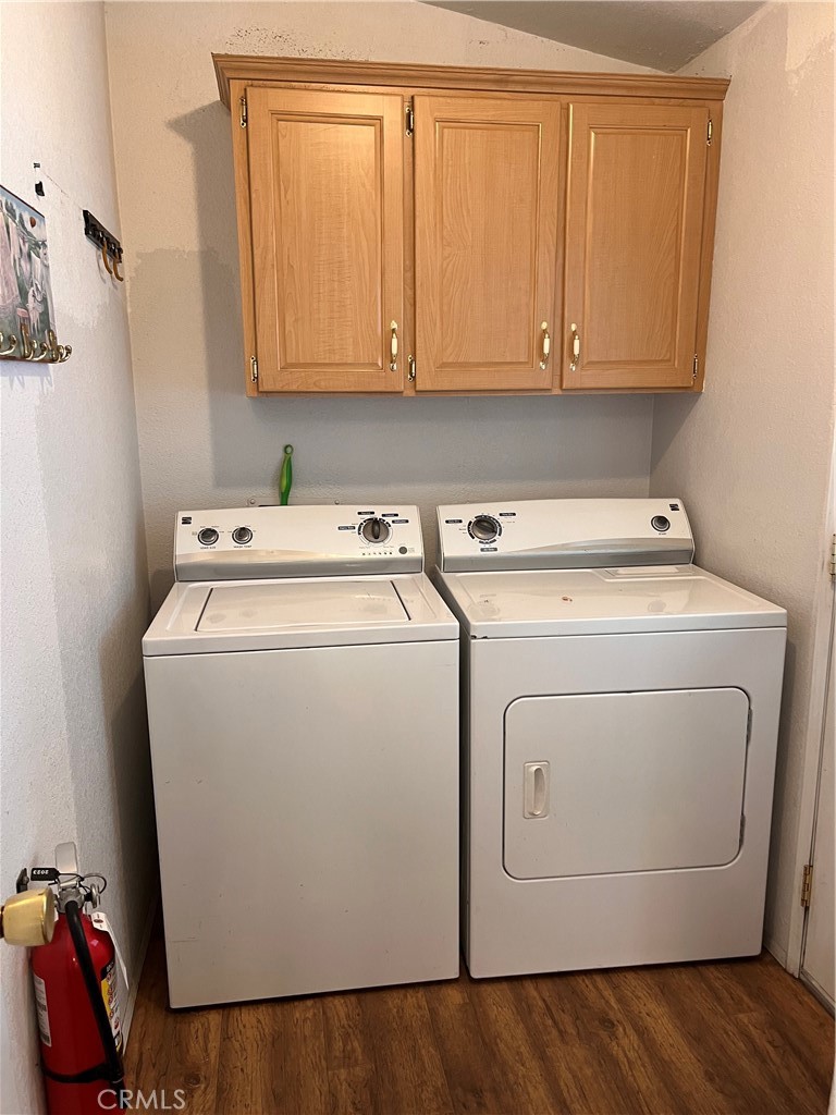 Laundry room with a white washer and dryer beneath wooden cabinets.