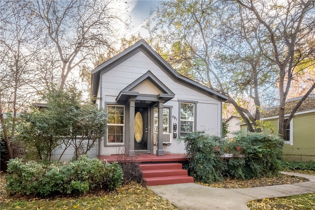 Light-gray gabled house with an oval-glass front door, red steps, and mature trees.