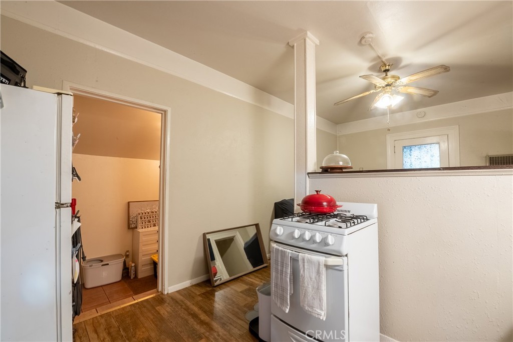Compact kitchen with a white gas range, refrigerator, and wood-look flooring.