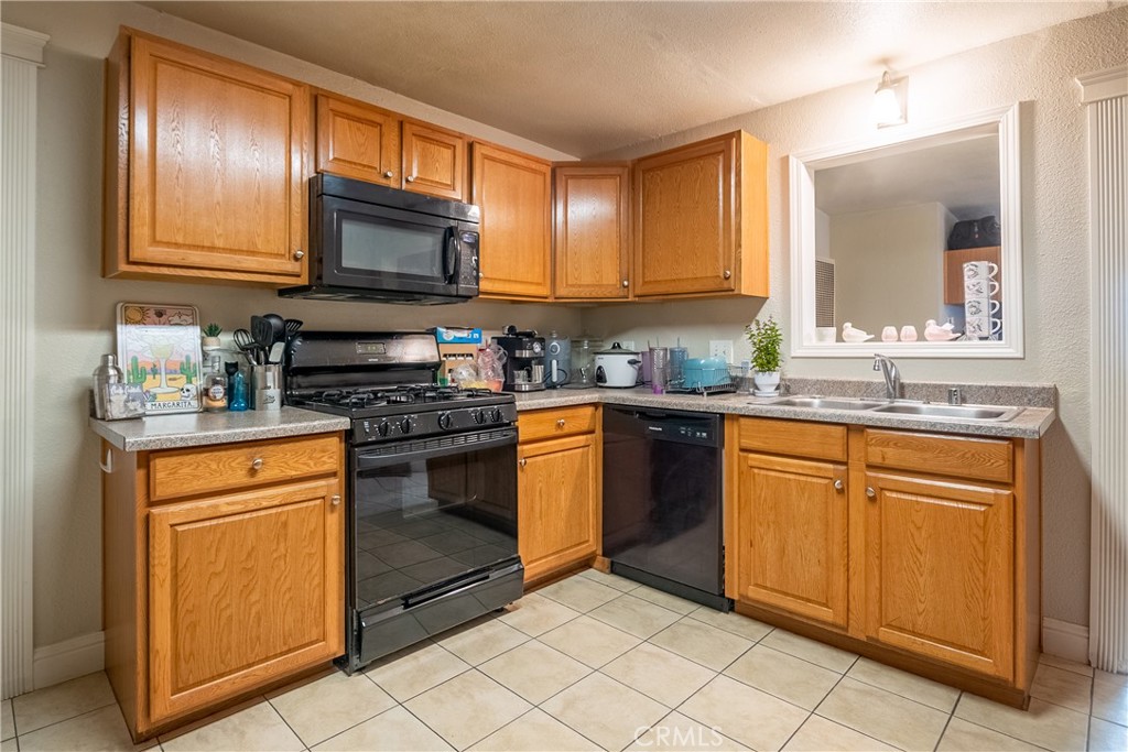 Kitchen with honey-colored wood cabinets, gas range, dishwasher, and sink beneath a pass-through window.