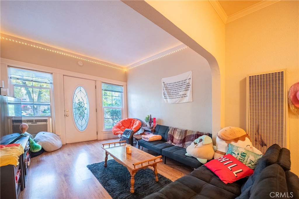 Living room with dark sectional sofas, a wood coffee table, ceiling string lights, and an oval-glass front door.