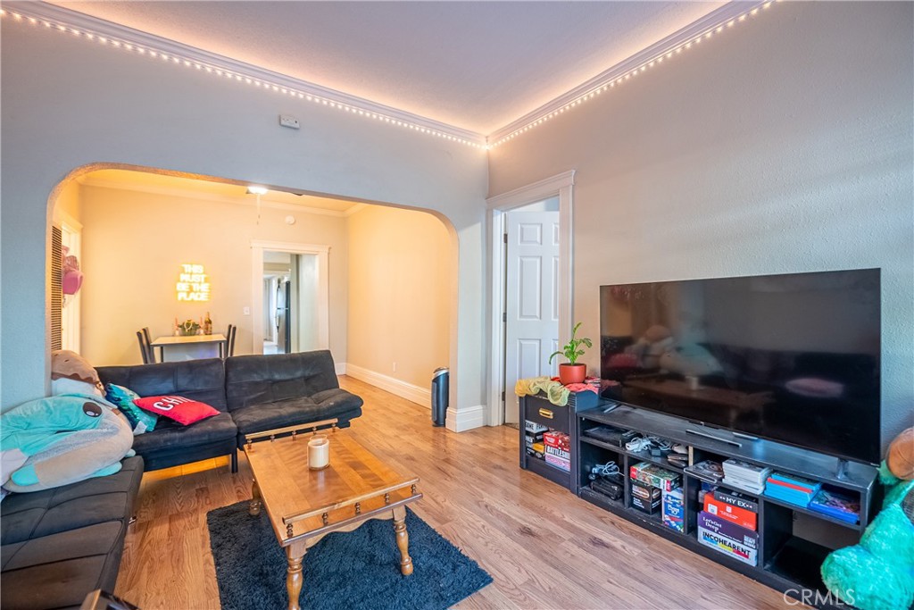 Living room with a dark sectional, wooden coffee table, television, and arched opening to the dining area.